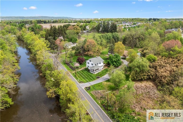 drone / aerial view of a nearby body of water and a tree filled landscape