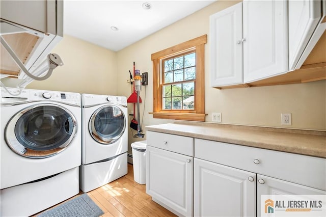 laundry room with cabinet space, washing machine and clothes dryer, light wood finished floors, and a baseboard heating unit