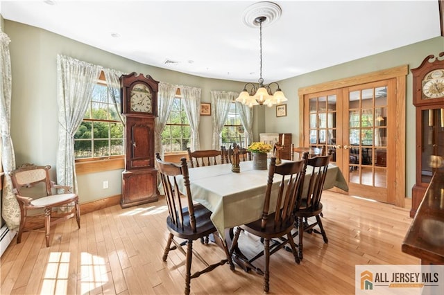 dining area featuring french doors, baseboards, light wood-type flooring, and a chandelier