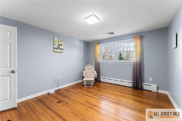 sitting room with visible vents, baseboards, baseboard heating, light wood-style floors, and a baseboard radiator