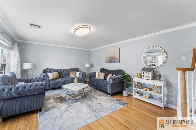 living area featuring visible vents, crown molding, baseboards, and wood finished floors