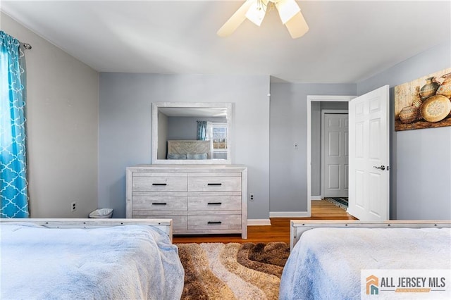 bedroom featuring a ceiling fan, baseboards, and wood finished floors