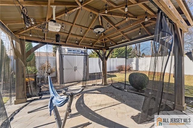 view of patio / terrace featuring a gazebo, a storage unit, a fenced backyard, and an outdoor structure