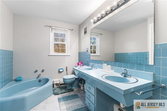 bathroom featuring a sink, visible vents, tile walls, and a bath