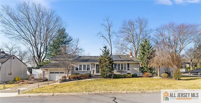 ranch-style house featuring solar panels, a front lawn, a garage, and driveway