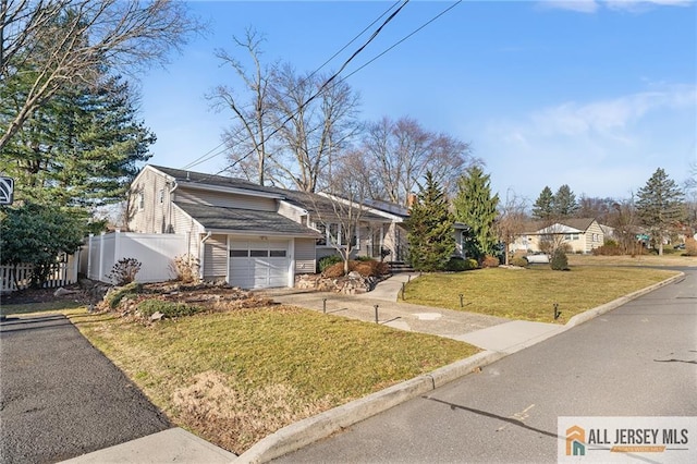 view of front of house with a garage, driveway, a front lawn, and fence