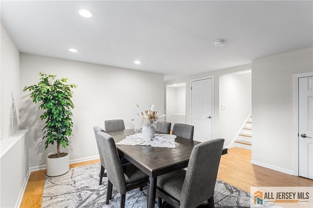 dining room with light wood finished floors, recessed lighting, stairs, and baseboards