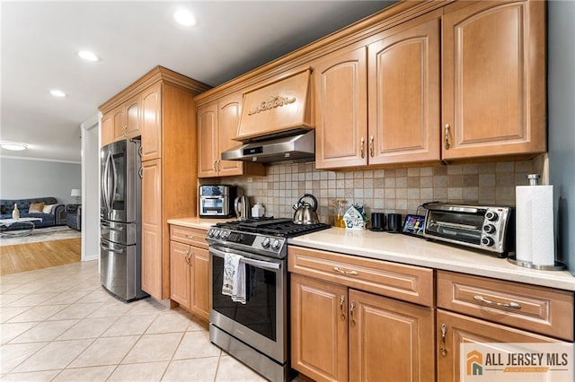 kitchen featuring under cabinet range hood, a toaster, appliances with stainless steel finishes, and light countertops