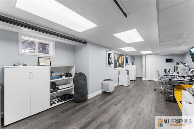 workout room with washer / dryer, a paneled ceiling, baseboards, and wood finished floors