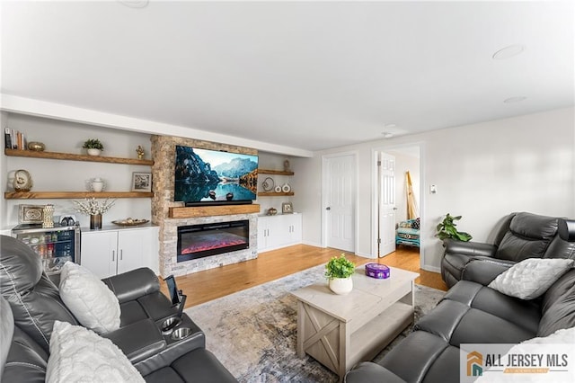 living area featuring light wood-style flooring, built in features, and a fireplace