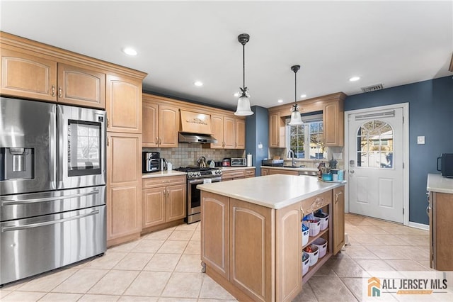 kitchen with under cabinet range hood, tasteful backsplash, a center island, appliances with stainless steel finishes, and light countertops