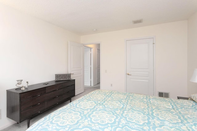 bedroom featuring light carpet and a textured ceiling