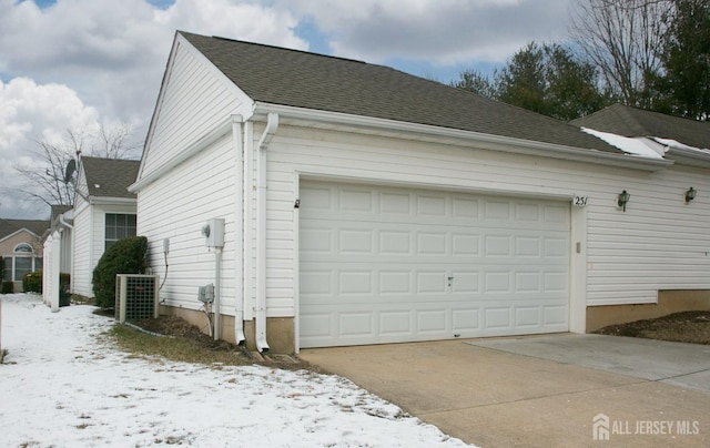 snow covered garage featuring central AC unit