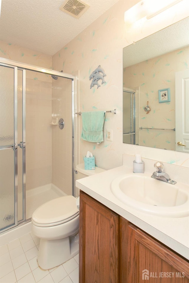 bathroom featuring vanity, toilet, an enclosed shower, and a textured ceiling