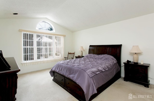 bedroom with lofted ceiling, light colored carpet, and a textured ceiling