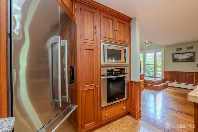 7 Finch Ct, West Windsor, NJ 08550 - kitchen with appliances with stainless steel finishes, a baseboard radiator, brown cabinetry, wainscoting, and light wood finished floors