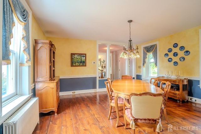 7 Finch Ct, West Windsor, NJ 08550 - dining area with radiator heating unit, dark wood-style flooring, ornate columns, and a chandelier