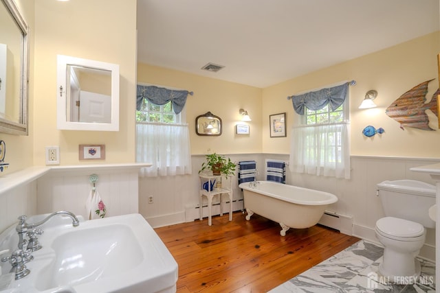 7 Finch Ct, West Windsor, NJ 08550 - bathroom featuring baseboard heating, a wainscoted wall, a soaking tub, wood-type flooring, and a decorative wall