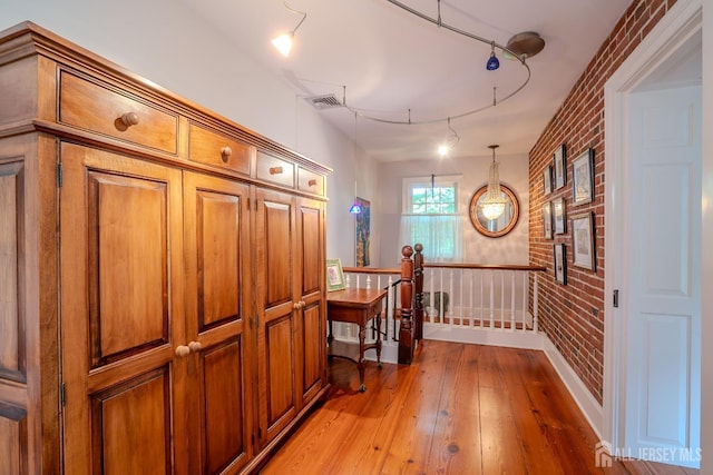 7 Finch Ct, West Windsor, NJ 08550 - hallway with brick wall, light wood finished floors, track lighting, and an upstairs landing