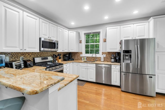 22 Daffodil Way, Old Bridge, NJ 08857 - kitchen with appliances with stainless steel finishes, a peninsula, white cabinets, light stone counters, and light wood finished floors