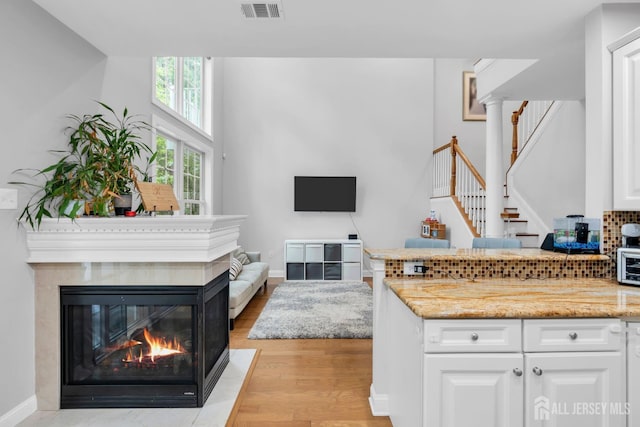 22 Daffodil Way, Old Bridge, NJ 08857 - kitchen featuring white cabinetry, light wood-style floors, light stone countertops, a multi sided fireplace, and open floor plan