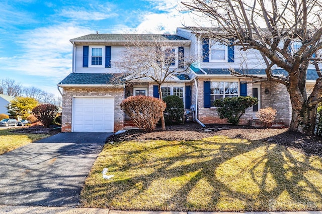 traditional home featuring an attached garage, brick siding, aphalt driveway, and a front yard