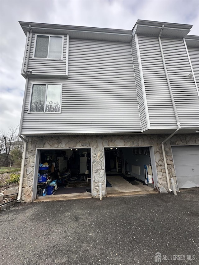 view of side of property with stone siding and a garage