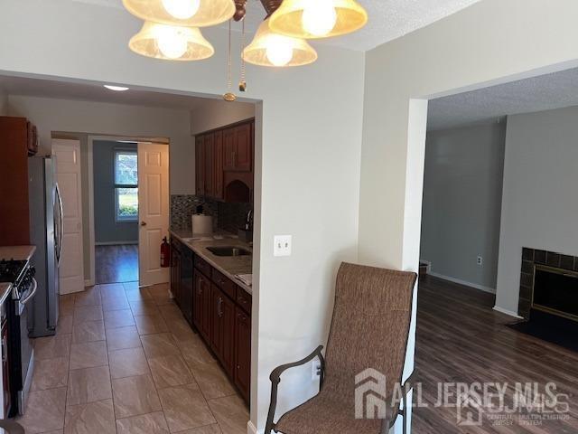 kitchen with backsplash, a textured ceiling, stainless steel appliances, sink, and hardwood / wood-style floors