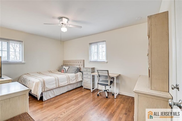 bedroom featuring ceiling fan, multiple windows, and light wood-style flooring