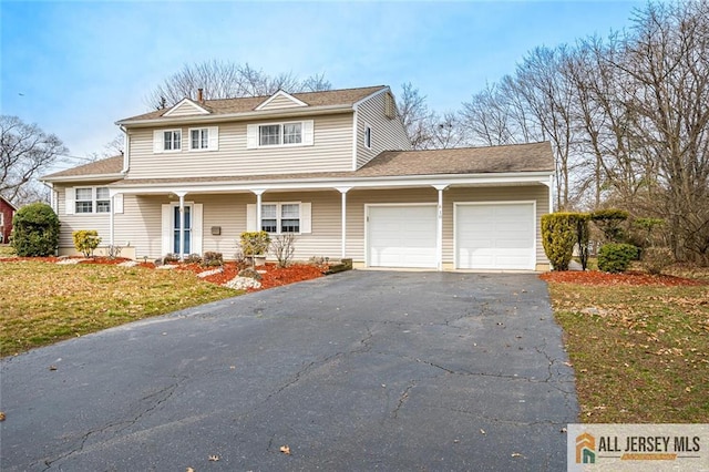 traditional-style home with an attached garage, a porch, a front yard, and driveway