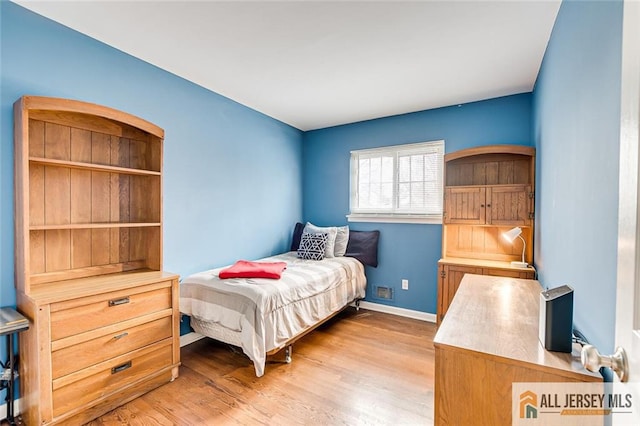 bedroom featuring light wood finished floors and baseboards