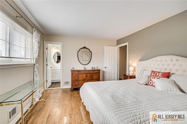 bedroom featuring ensuite bath, light wood-style floors, and visible vents