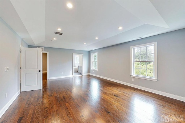 spare room with dark wood-type flooring and a tray ceiling