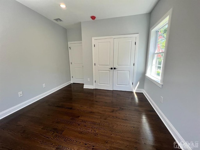 unfurnished bedroom featuring a closet and dark wood-type flooring