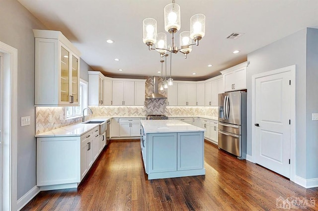 kitchen with stainless steel fridge with ice dispenser, pendant lighting, dark wood-type flooring, and wall chimney range hood