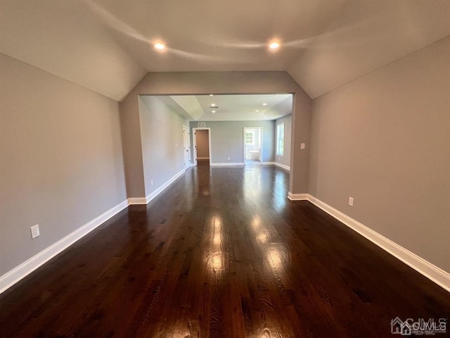 additional living space with dark wood-type flooring and vaulted ceiling