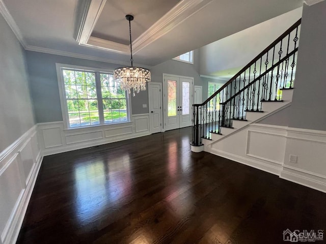 unfurnished dining area featuring a notable chandelier, a healthy amount of sunlight, dark hardwood / wood-style floors, and a tray ceiling