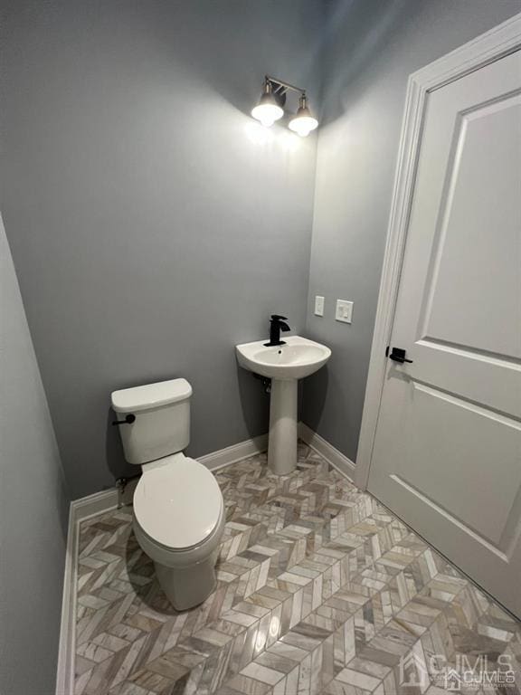 bathroom featuring parquet flooring and toilet