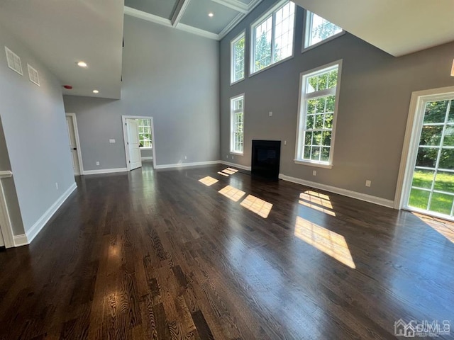 unfurnished living room featuring beamed ceiling, a towering ceiling, dark hardwood / wood-style flooring, and coffered ceiling