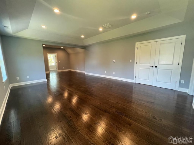 interior space with dark hardwood / wood-style flooring and a raised ceiling