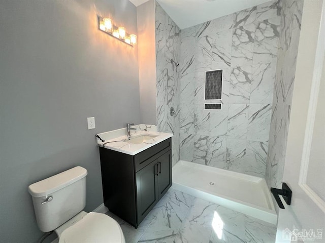 bathroom with vanity, tile patterned floors, a tile shower, and toilet