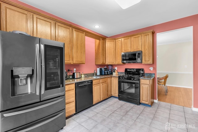 kitchen featuring black appliances, light stone countertops, a sink, recessed lighting, and baseboards