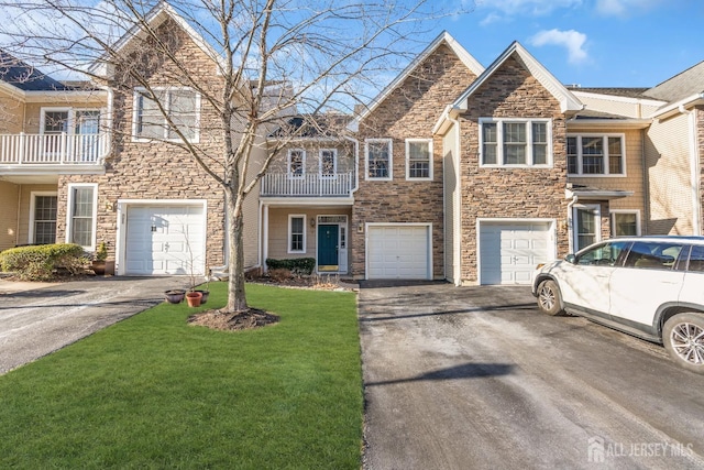 multi unit property with driveway, stone siding, a garage, and a front yard