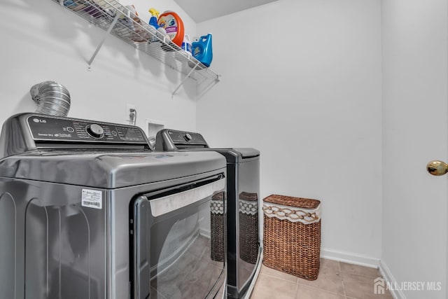 laundry area featuring washing machine and dryer, baseboards, and tile patterned floors