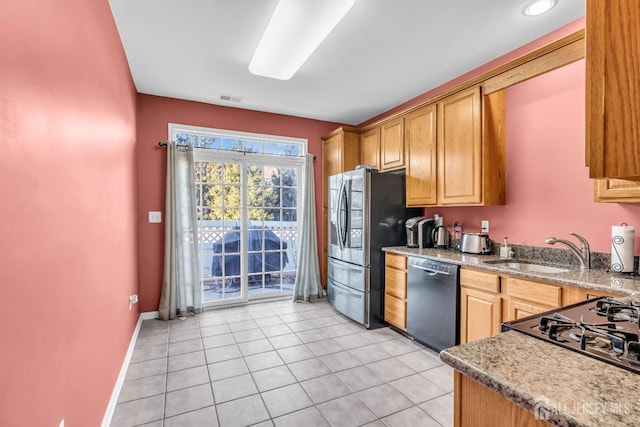 kitchen with black dishwasher, a sink, stainless steel fridge, light tile patterned floors, and light stone countertops