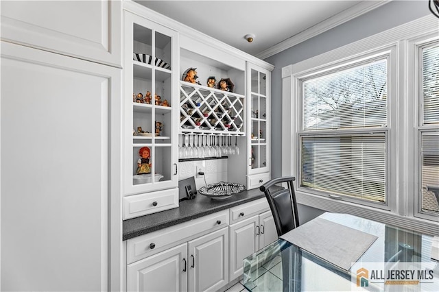 bar featuring crown molding and white cabinets