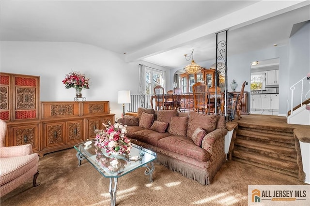 living room with a notable chandelier, lofted ceiling with beams, plenty of natural light, and carpet floors