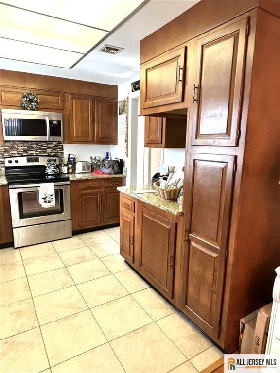 156 Pelham Ln Unit 156N, Monroe, NJ 08831 - kitchen featuring stainless steel appliances, light tile patterned flooring, light stone countertops, and tasteful backsplash