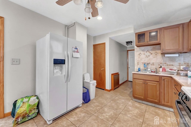 kitchen with white refrigerator with ice dispenser, ceiling fan, stainless steel range with electric cooktop, light tile patterned flooring, and tasteful backsplash