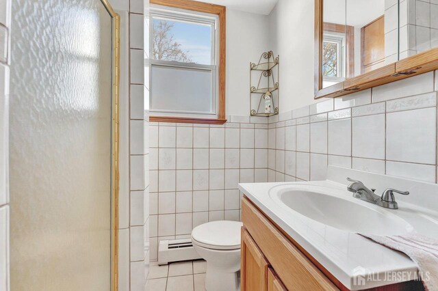 bathroom featuring tile walls, a shower with door, tile patterned floors, a baseboard radiator, and vanity